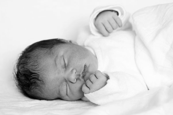 Foto: Wilhelm Watschka Fotografie I Dieses Bild zeigt ein neugeborenes Kind, welches im Bett liegt und schläft. Newborn Bild in schwarz weiss.