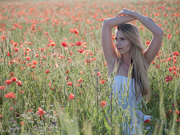 Foto: Wilhelm Watschka Fotografie. Portrait einer Frau mit über den Kopf überkreuzten Armen in einem Blumenfeld, Aufgenommen in Groß Enzersdorf - Niederösterreich