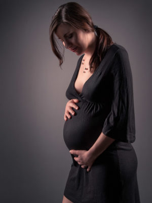 Fotograf: Wilhelm Watschka Fotografie I Eine schwangere Frau streichelt zärtlich mit ihren Händen über ihren Babybauch.